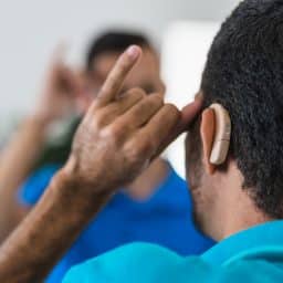 a man with hearing aids looks in the mirror
