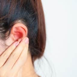 Woman holds ear in pain