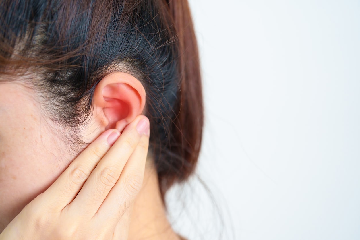 Woman holds ear in pain