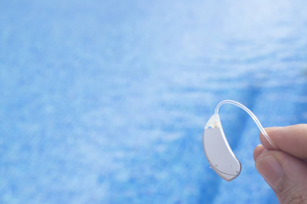 Man holding a hearing aid above a pool