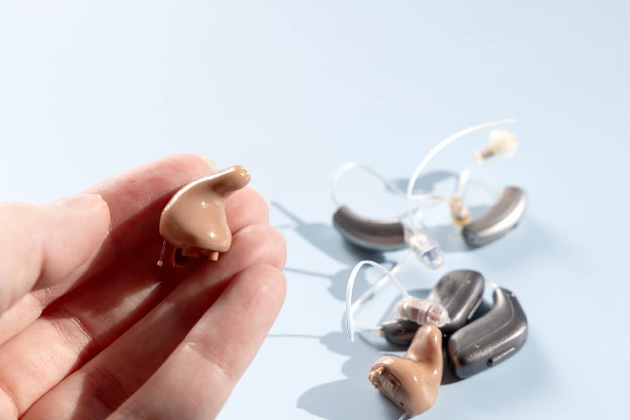 Hand holding modern hearing aid.